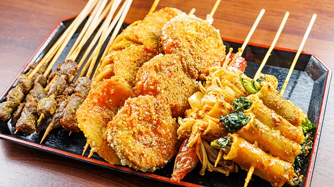 衣をまとった串料理が皿に並び、揚げたての質感が見える料理写真